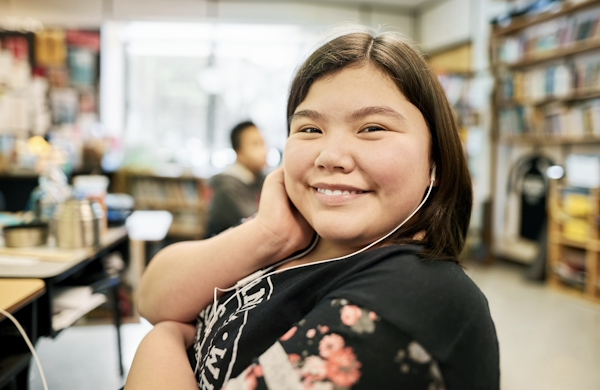 Happy girl in classroom wearing earphones